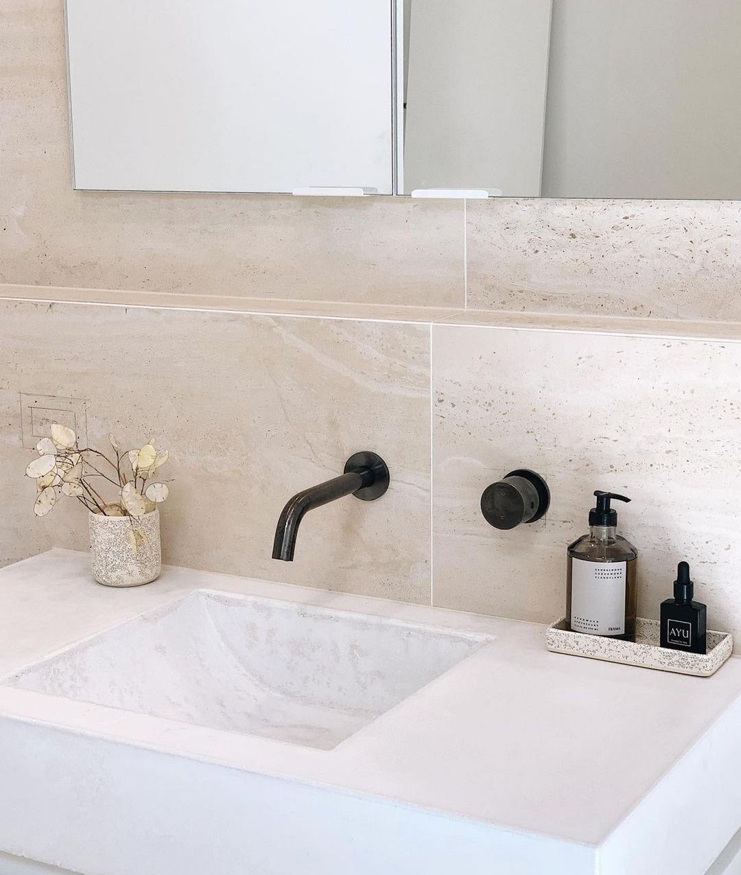 A bathroom sink with a soap dispenser and a vase of flowers