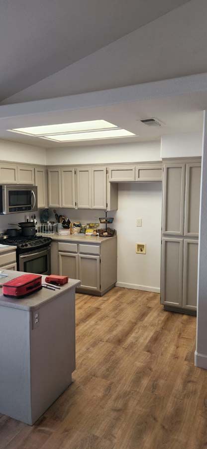 A kitchen with gray cabinets and wooden floors.