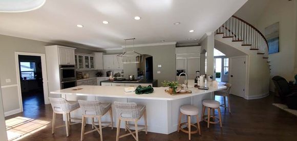 A kitchen with a large island and stairs in the background.