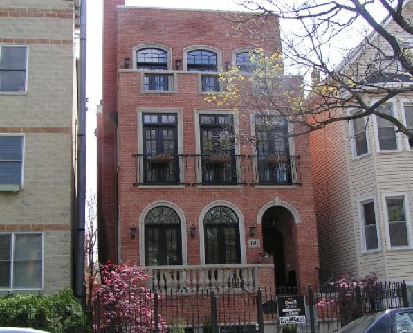 A brick building with arched windows and a balcony