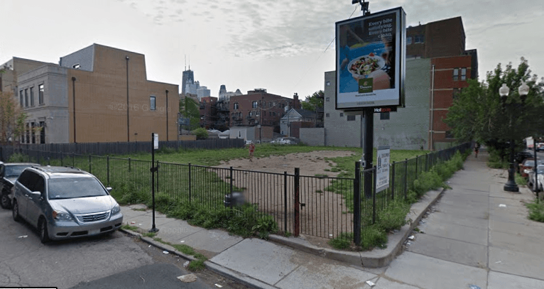 A van is parked on the side of the road in front of a vacant lot.