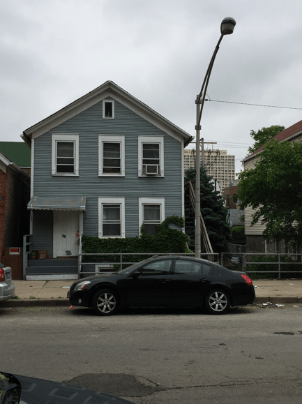 A black car is parked in front of a grey house
