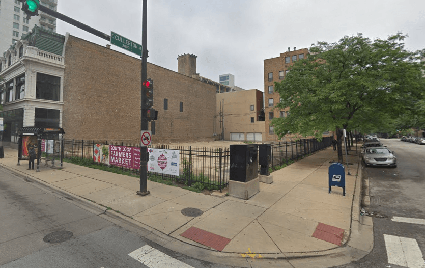A street corner with a building in the background and a blue mailbox in the foreground.
