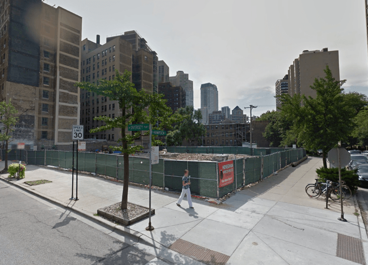 A man is walking down a sidewalk in front of a construction site.