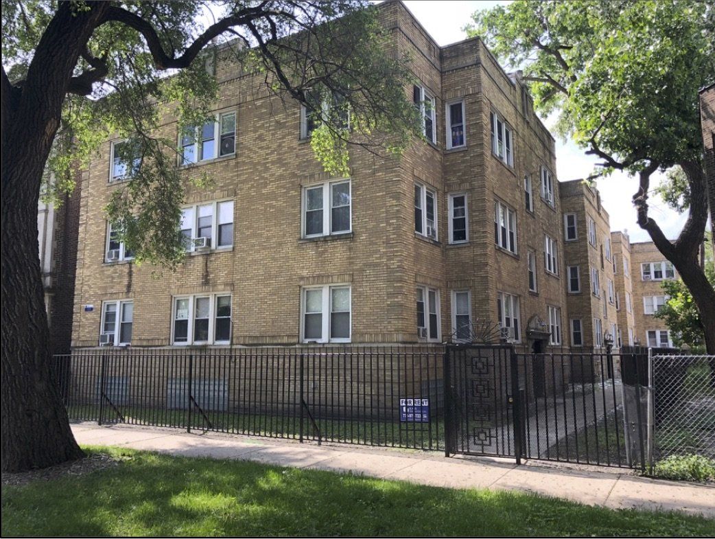 A large brick building with a fence around it and a tree in front of it.