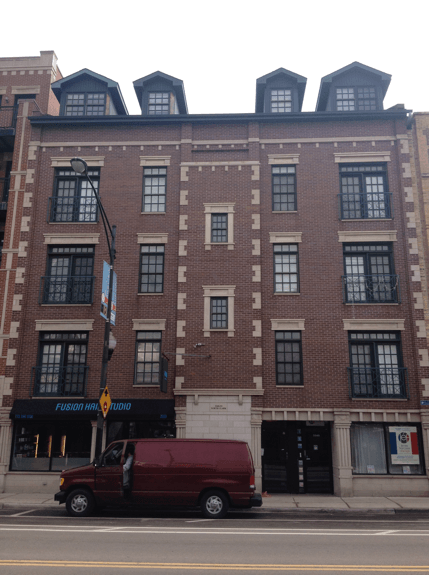 A red van is parked in front of a large brick building