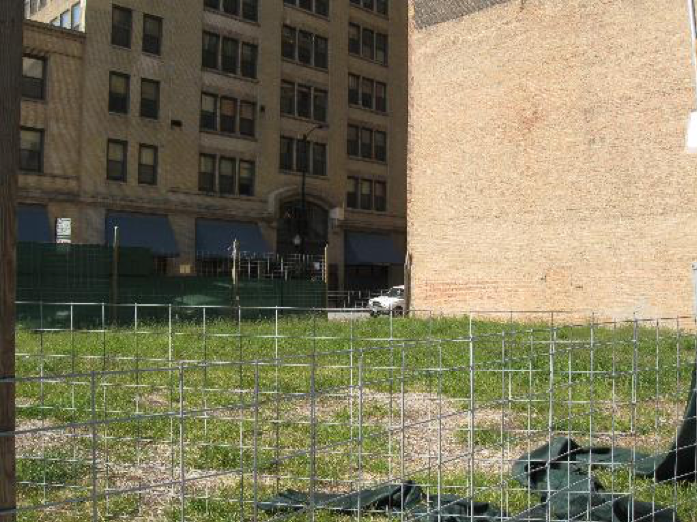 A fenced in area with a brick building in the background