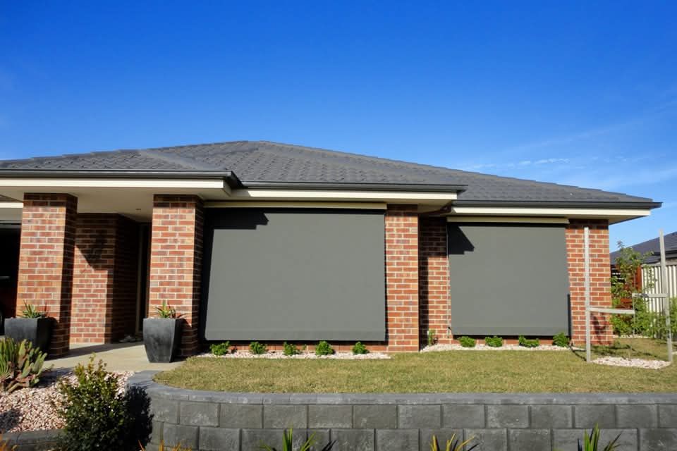 A brick house with gray blinds on the windows