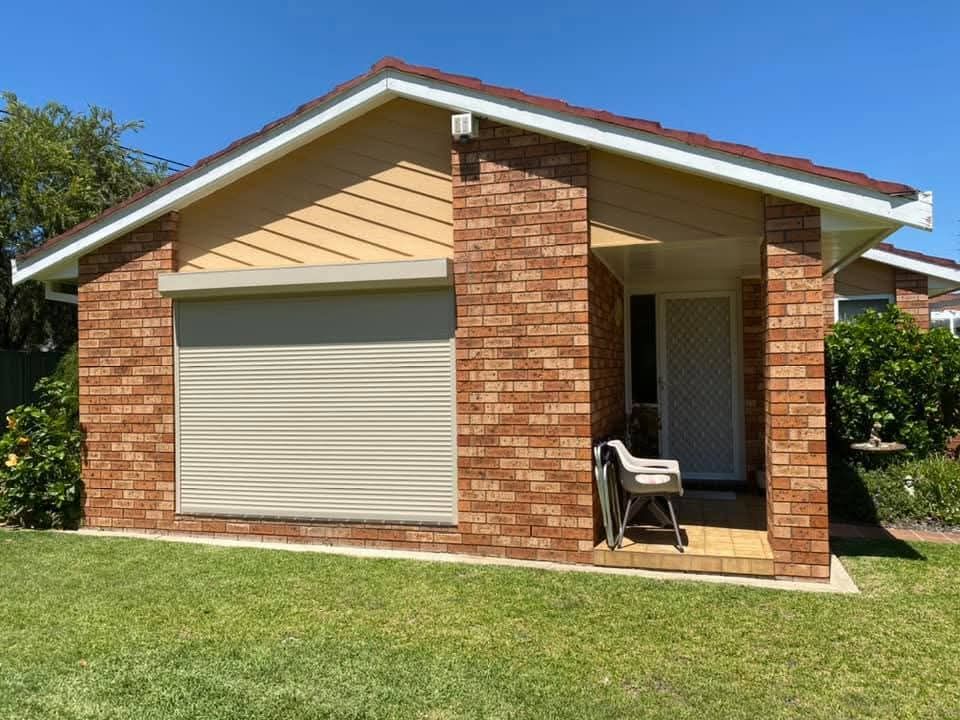 A brick house with a white garage door and a lawn in front of it.
