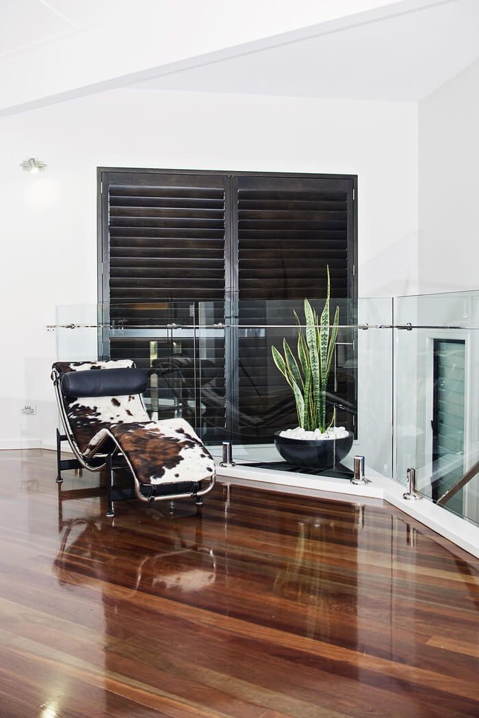 A chair is sitting on a wooden floor next to a glass railing.
