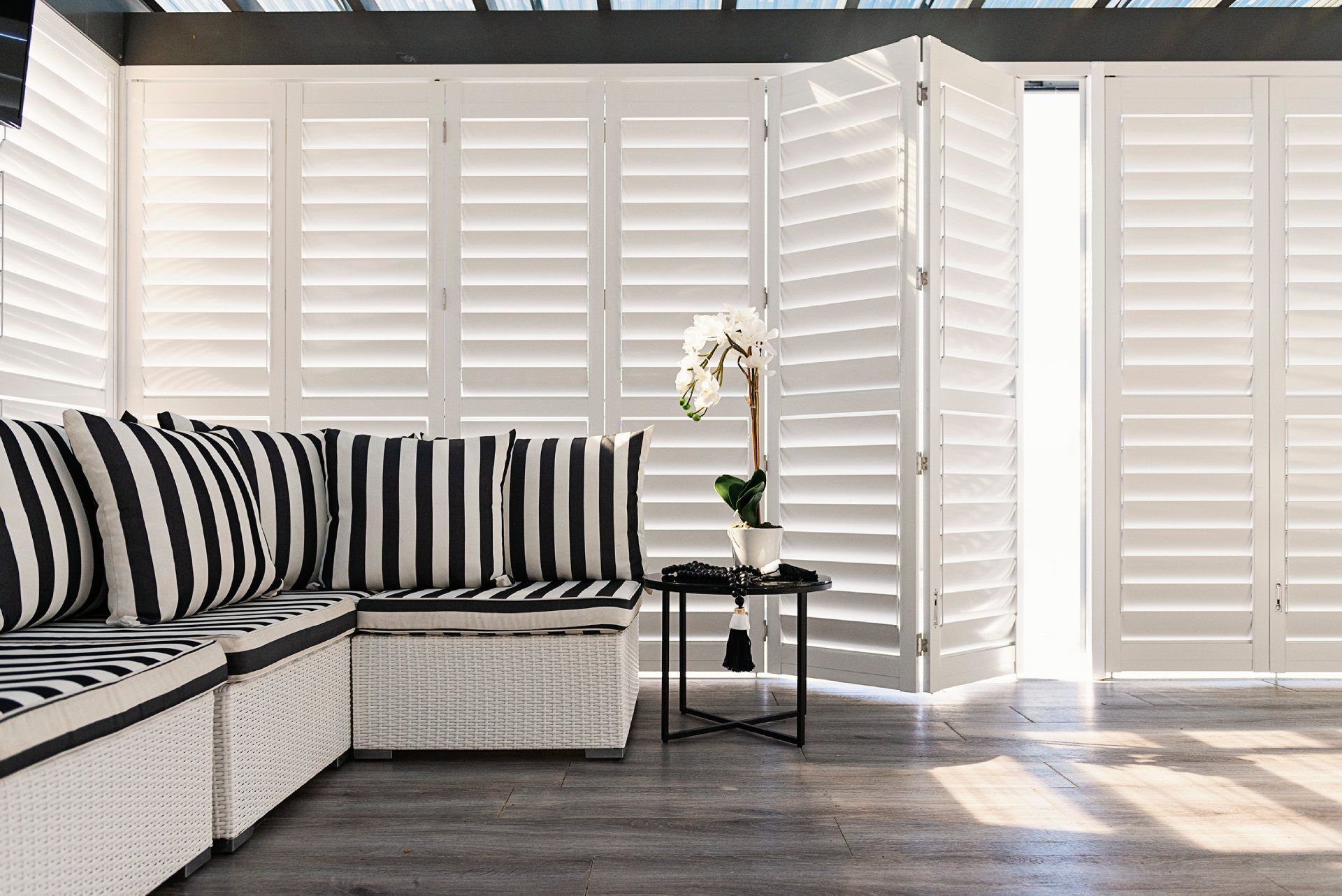 A living room with a couch , table and shutters.