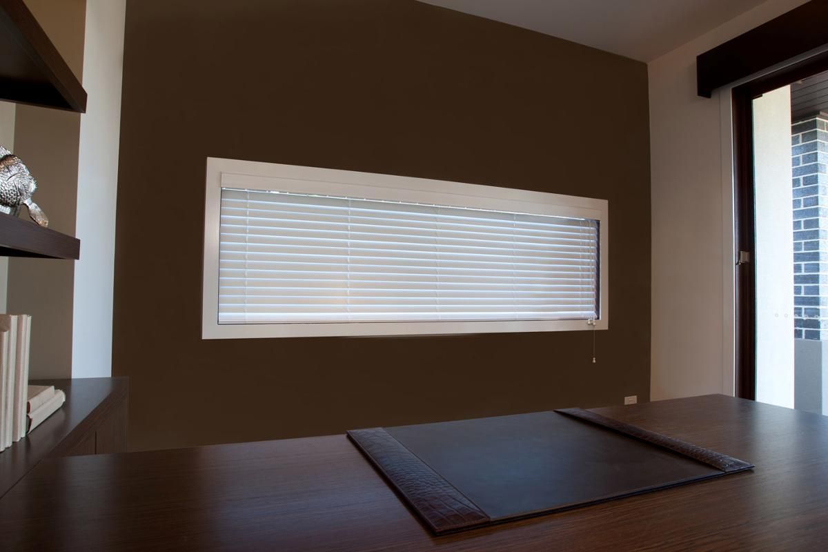 A room with a desk and a window with blinds