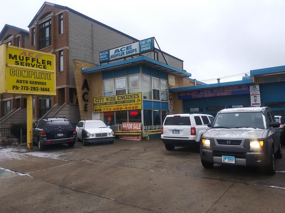 Several cars are parked in front of a building that says muffler service