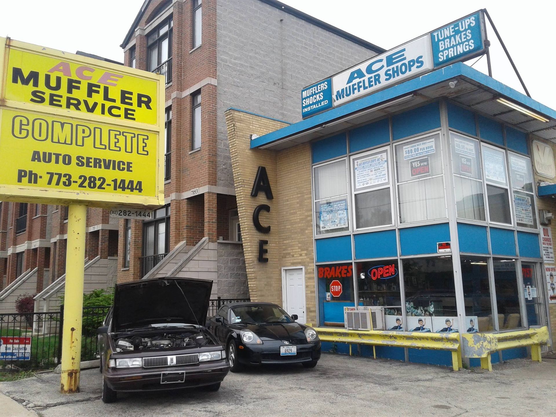 A car is parked in front of a muffler service complete auto service