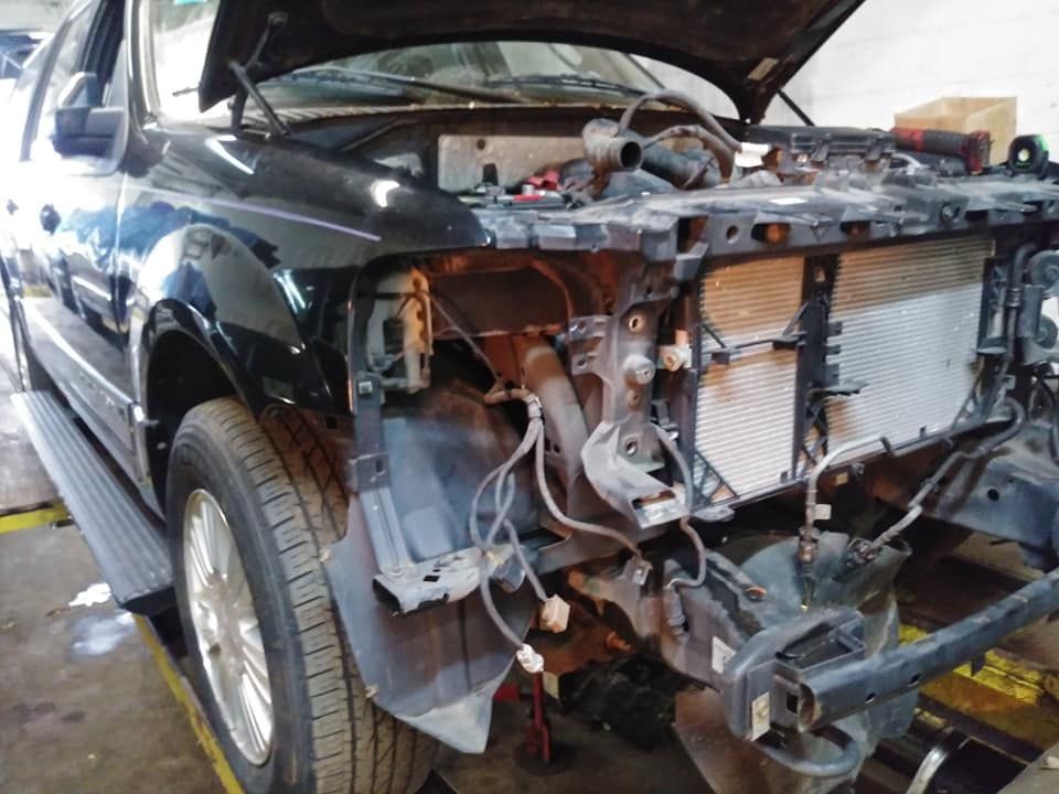 A black truck with the hood open is being worked on in a garage