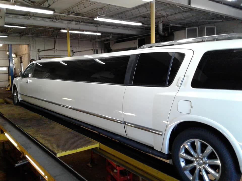 A white limousine is parked on a lift in a garage.