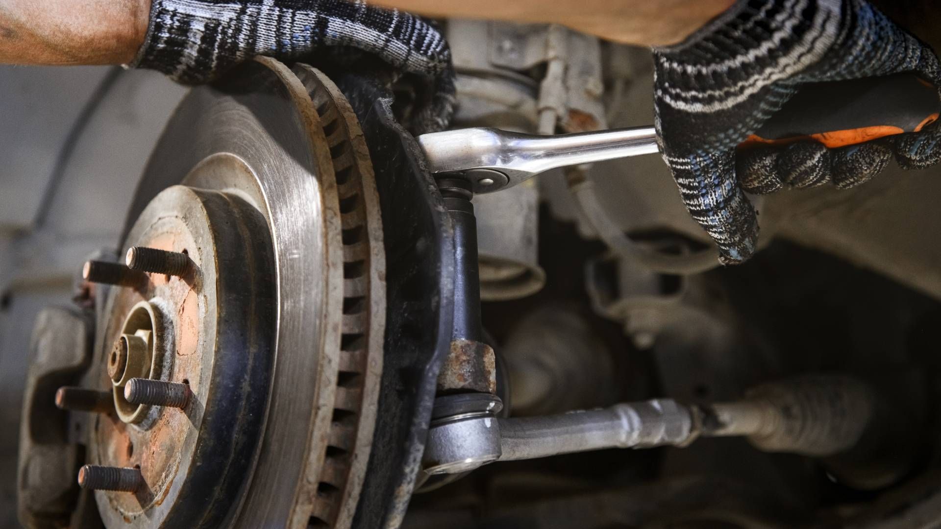 A man is working on a car with a wrench.