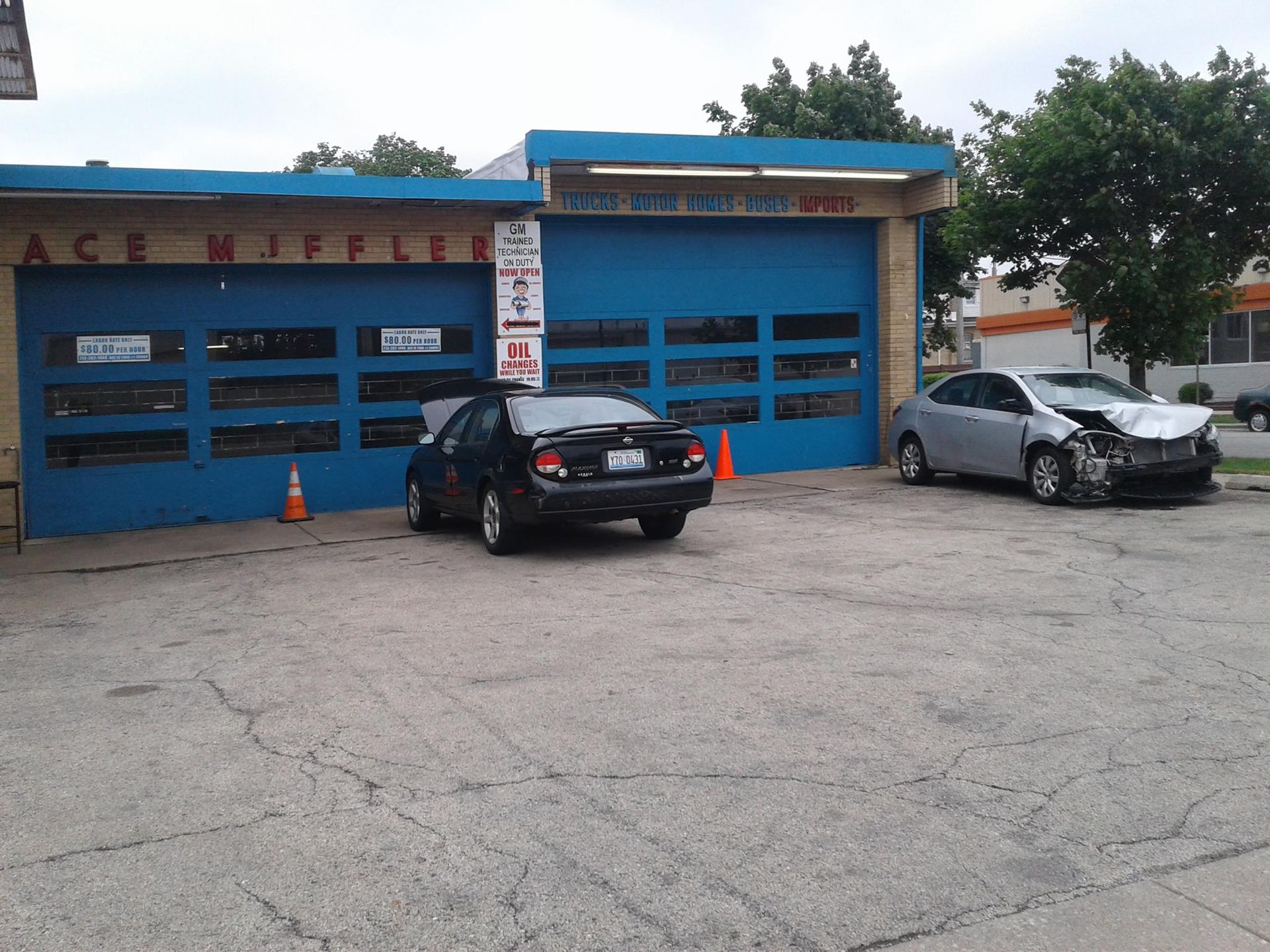 Two cars are parked in front of a garage that says ace mifflin