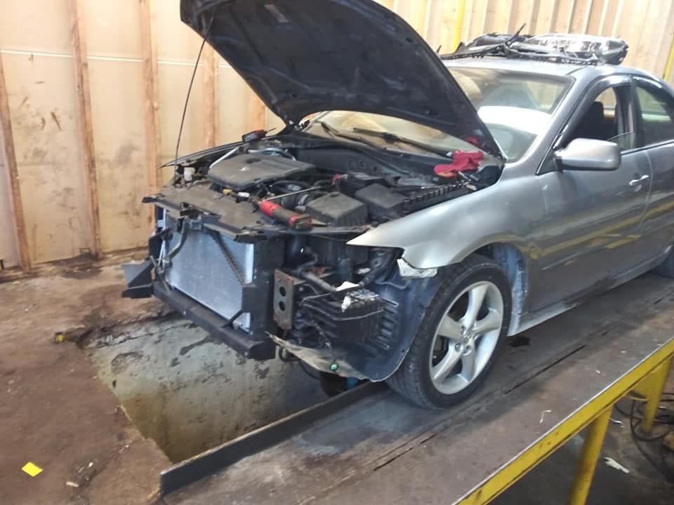 A car with the hood up is sitting on a ramp