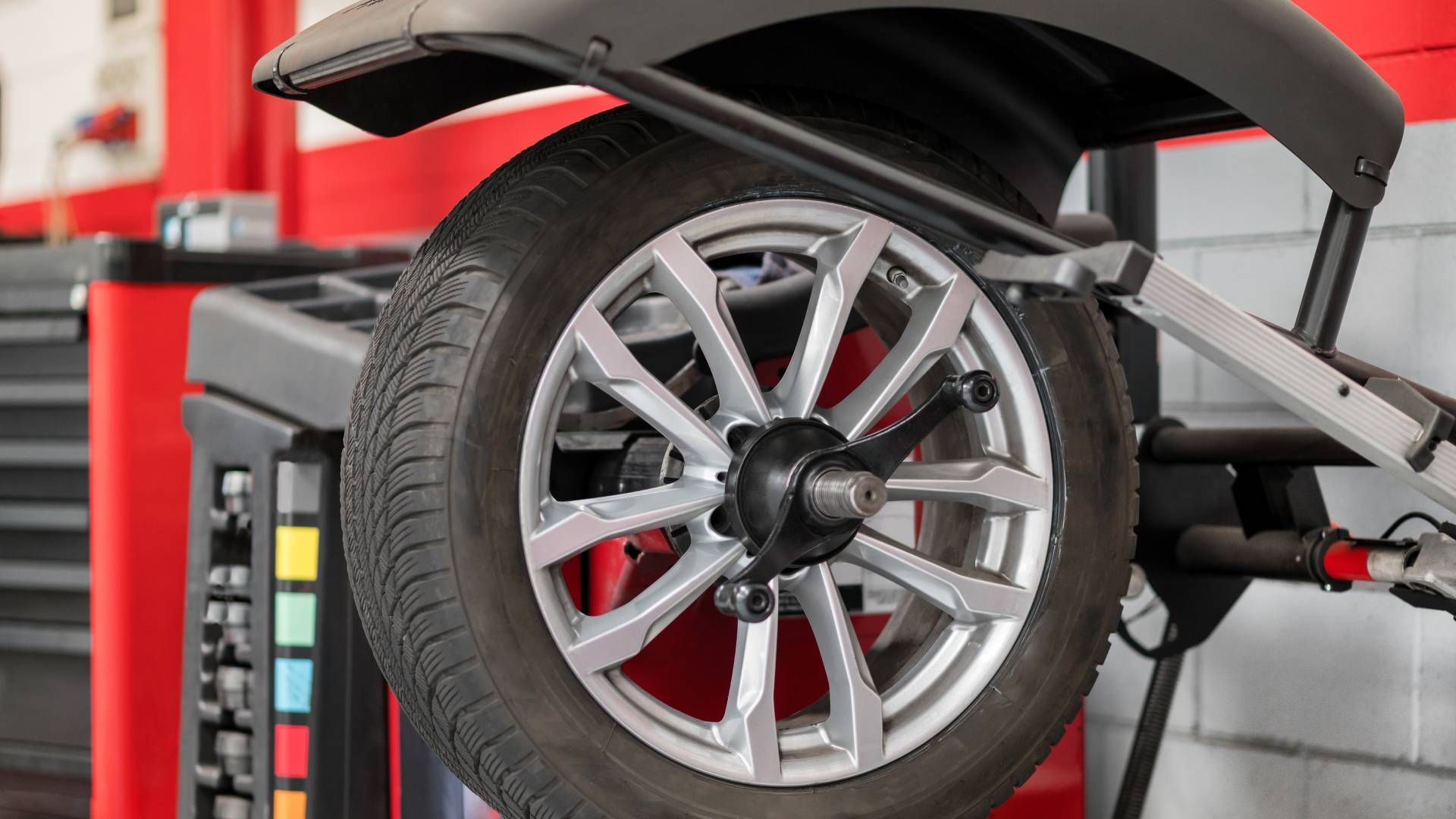 A car wheel is being balanced on a machine in a garage.