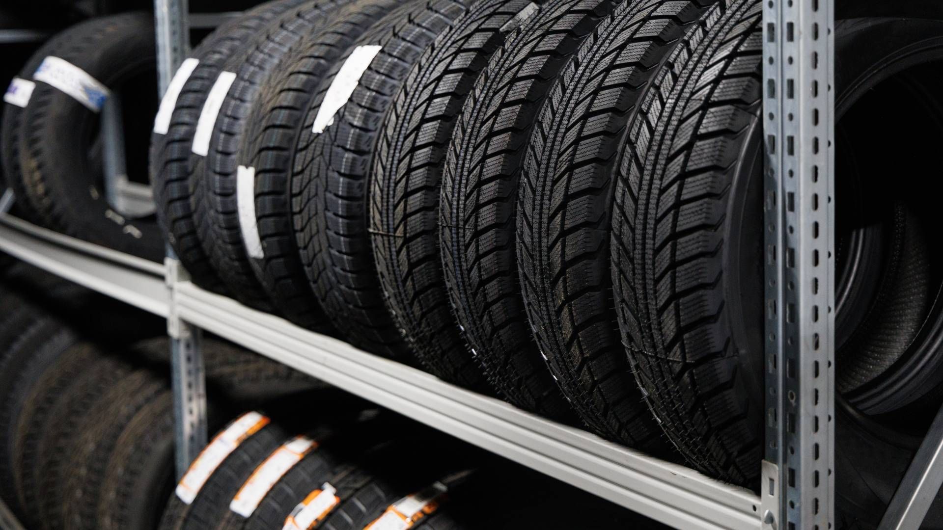 A row of tires are stacked on top of each other on a shelf.