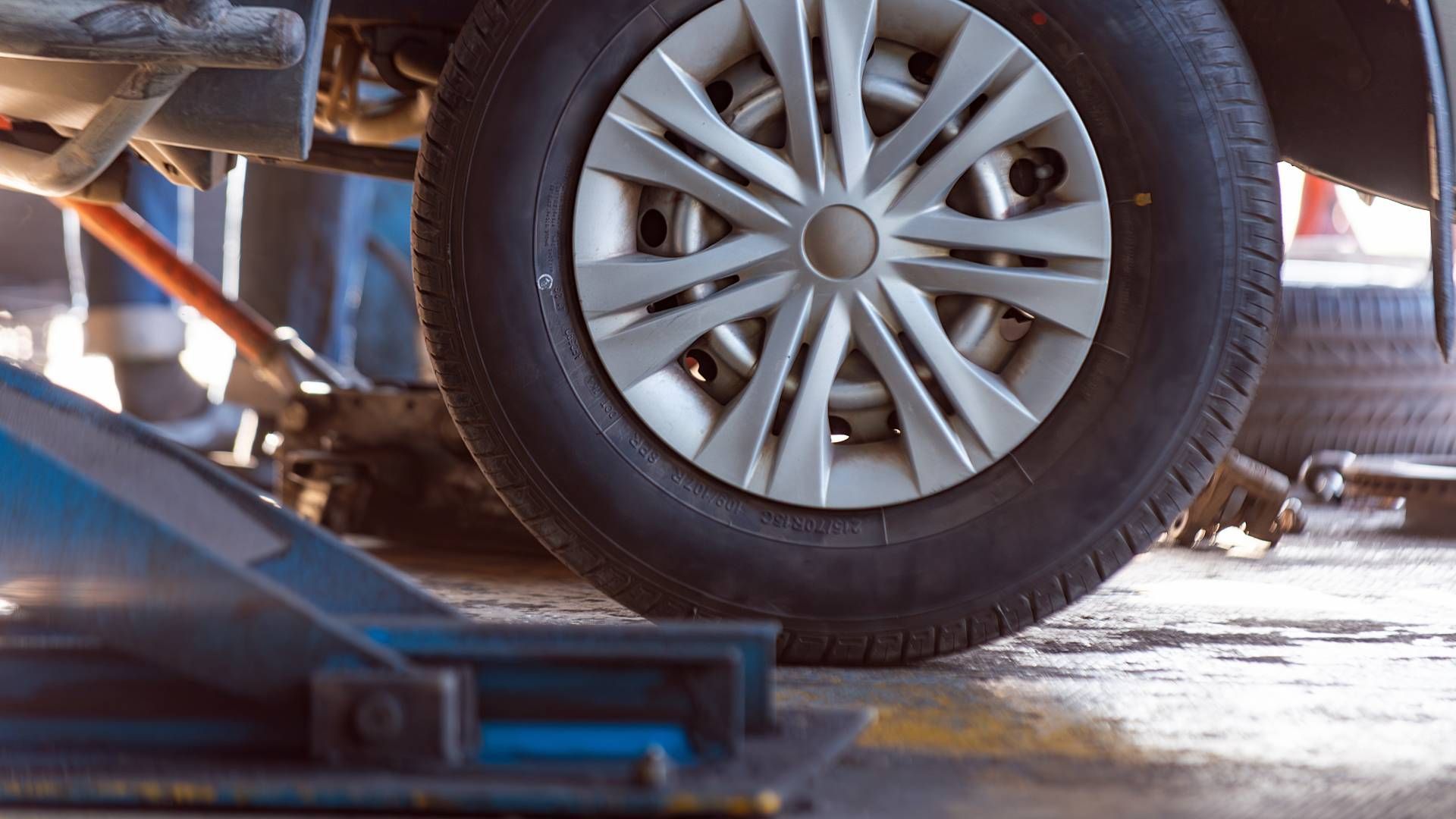 A close up of a car wheel on a lift in a garage.