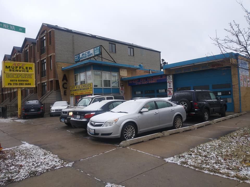 A row of cars are parked in front of a muffler repair shop.
