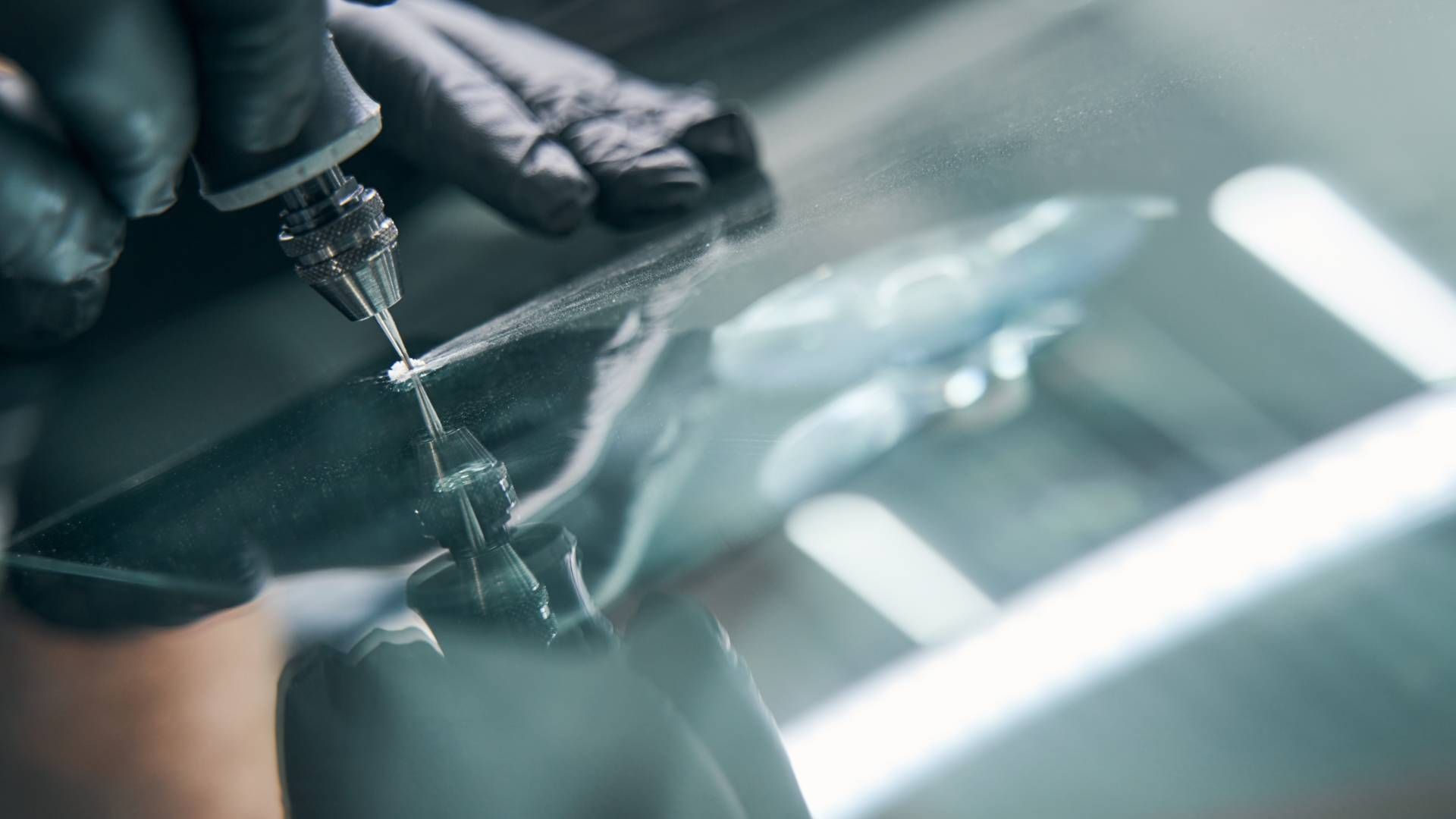 A person is repairing a windshield with a tool.