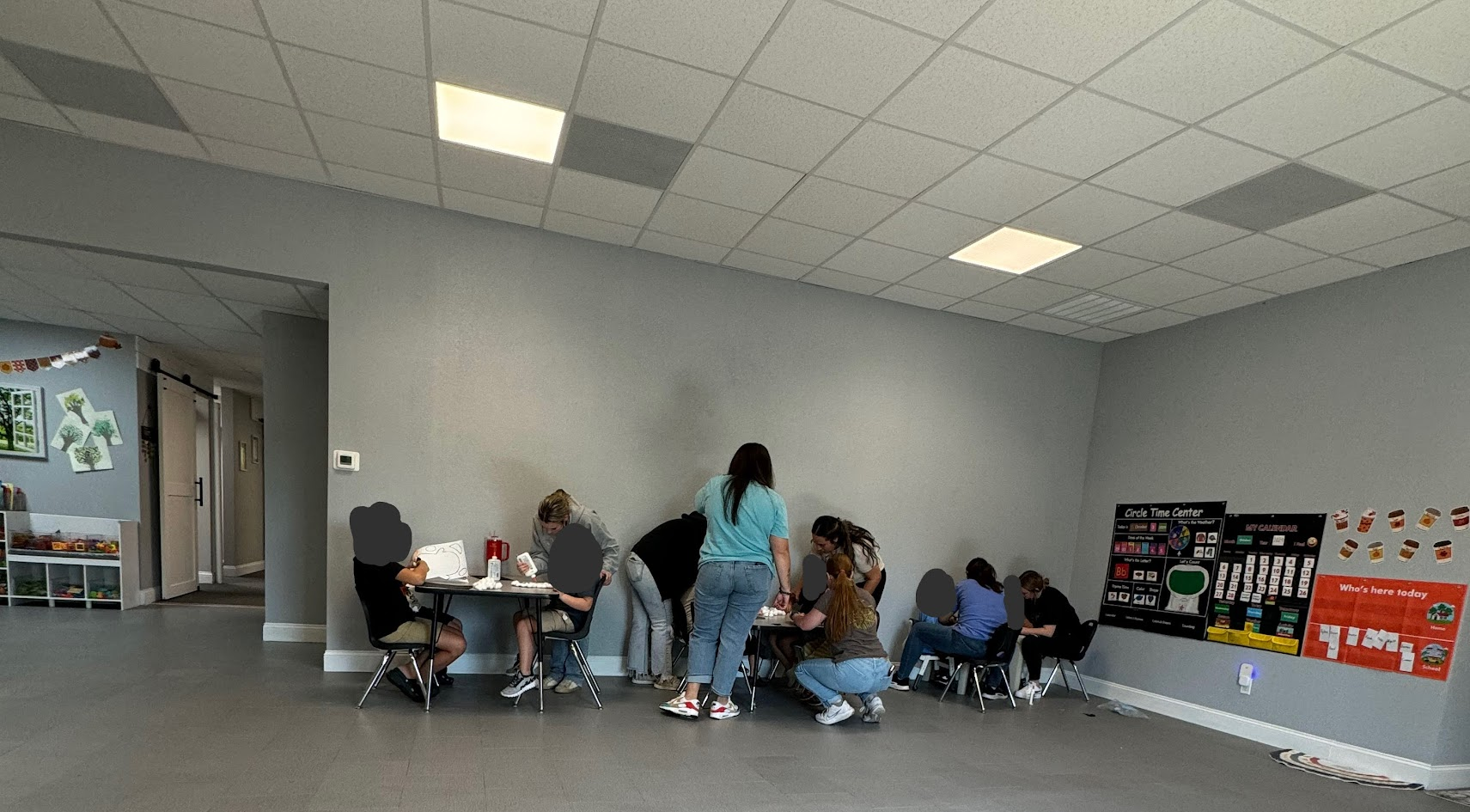 People gathered around a table, likely crafting, in a brightly lit room.