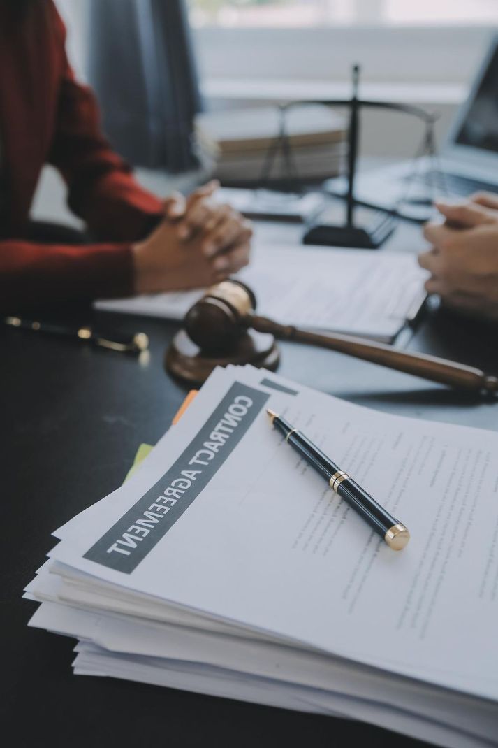 Contract agreement documents on a desk with a gavel and people discussing.