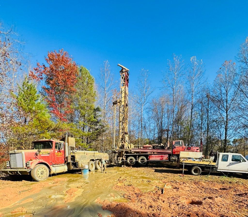 A truck is parked next to a drilling rig in a field.
