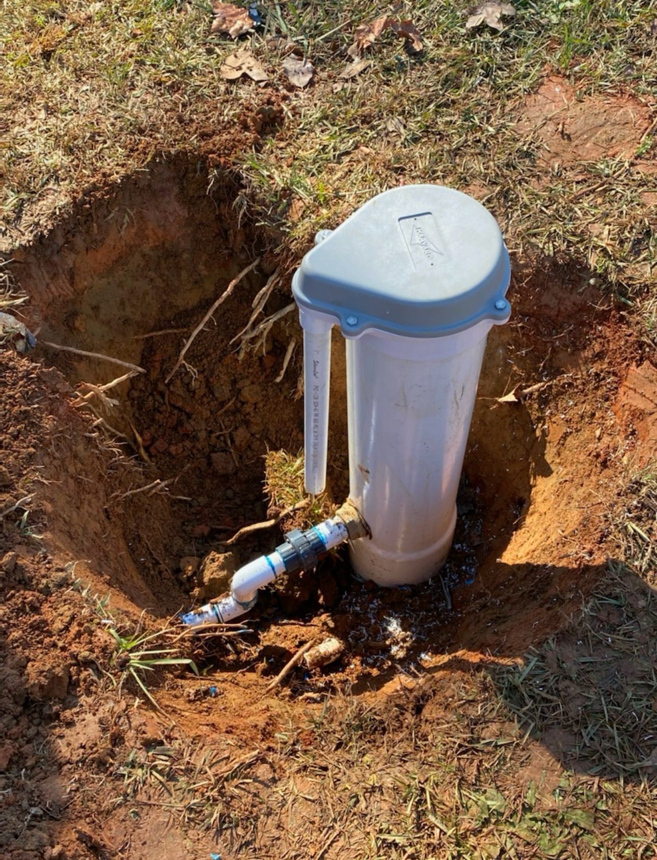 A white pipe is sitting in a hole in the ground.