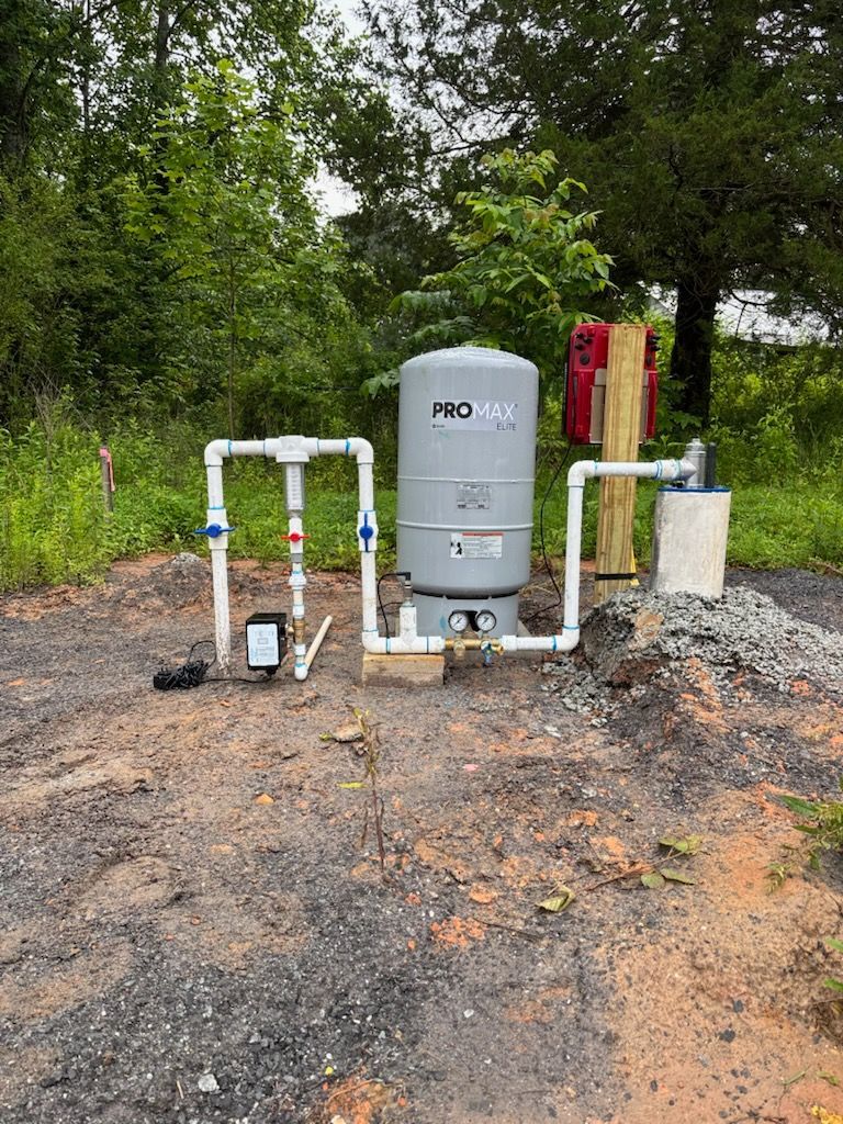 A water pump is sitting in the middle of a dirt field.