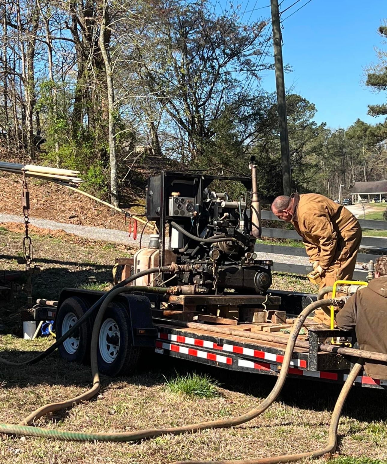 A red truck is parked in a field next to a tree.