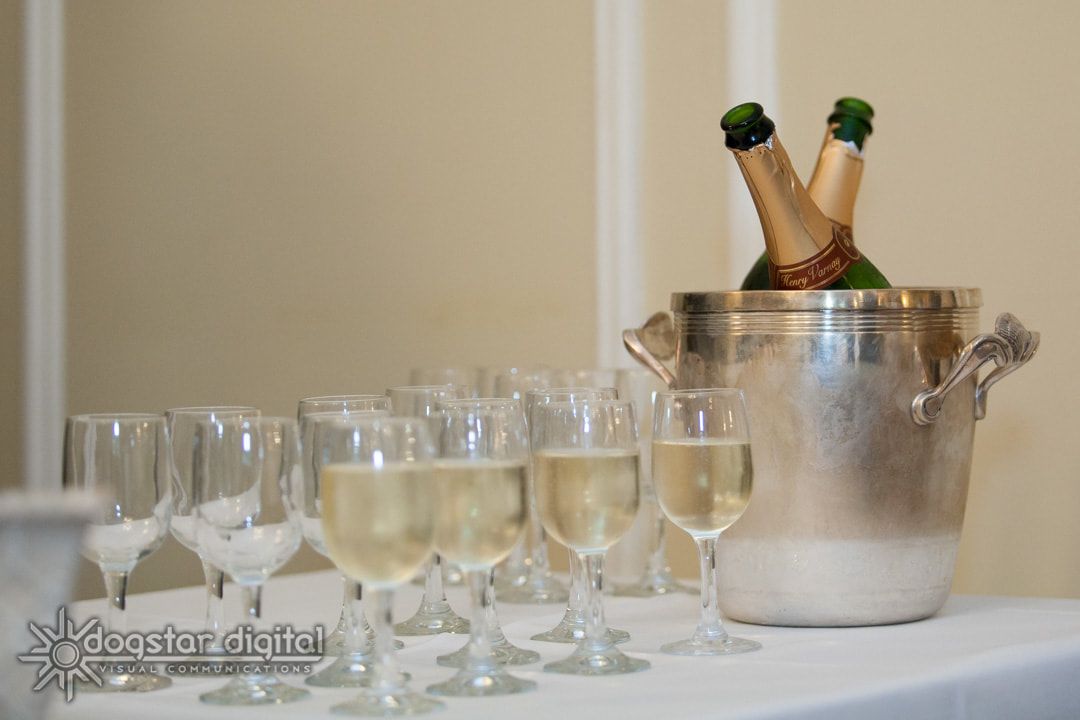 Champagne flutes filled with sparkling wine, alongside a bucket holding champagne bottles.