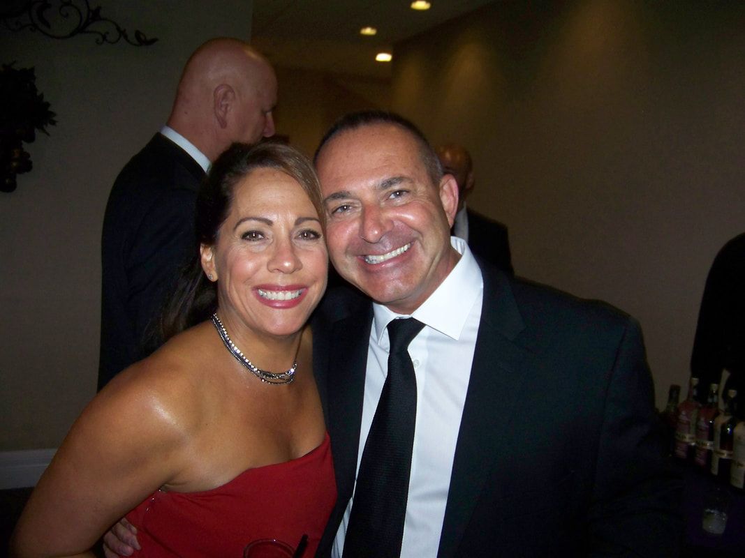Smiling couple in formal attire, woman in red, man in black suit, indoors.