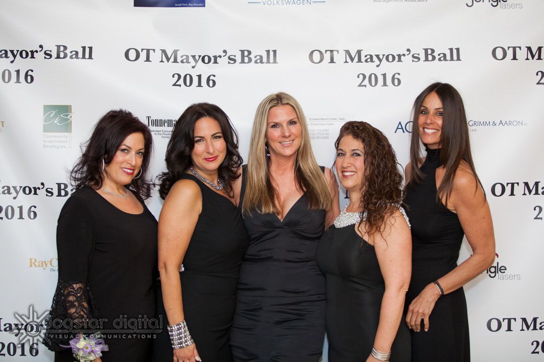 Five women in black dresses pose at the 