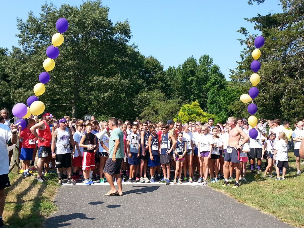 Runners at a starting line under balloon arches. Forest background.