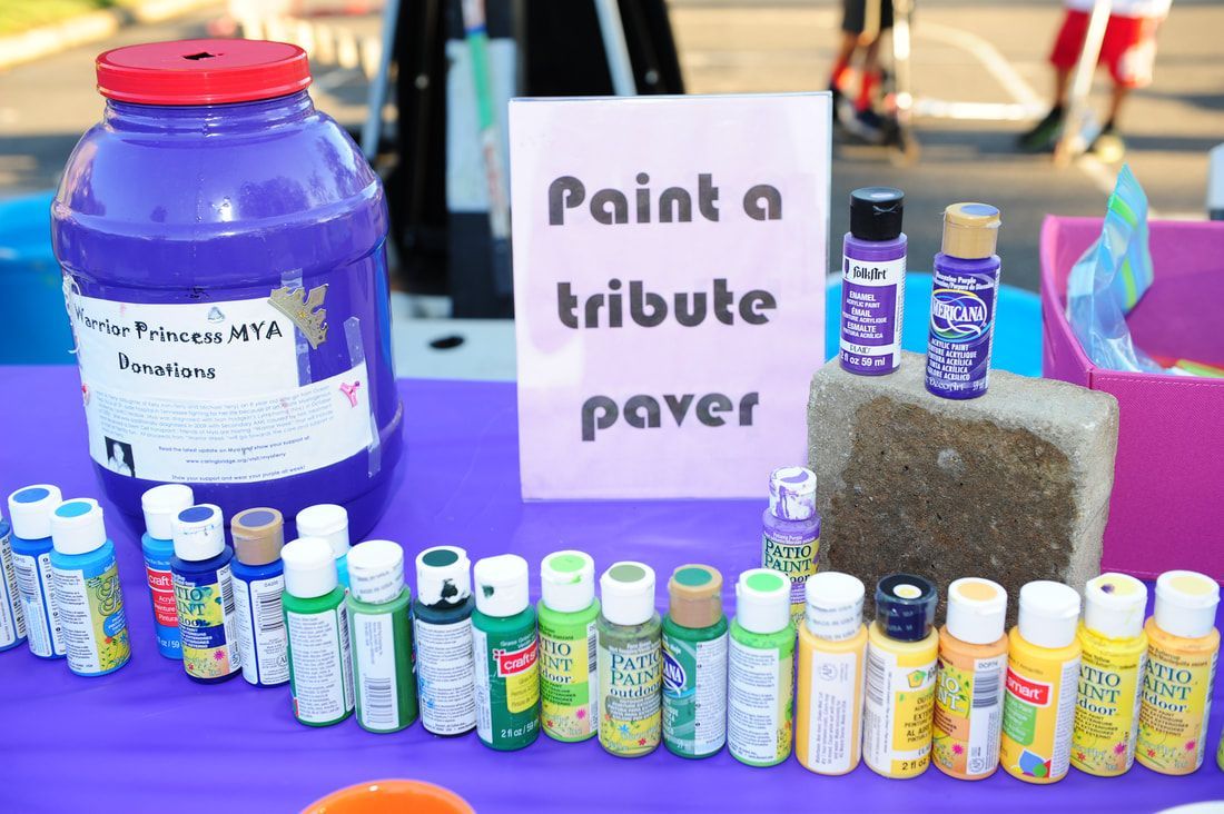 Table with paint jars, a purple paint bucket, and a sign that says 