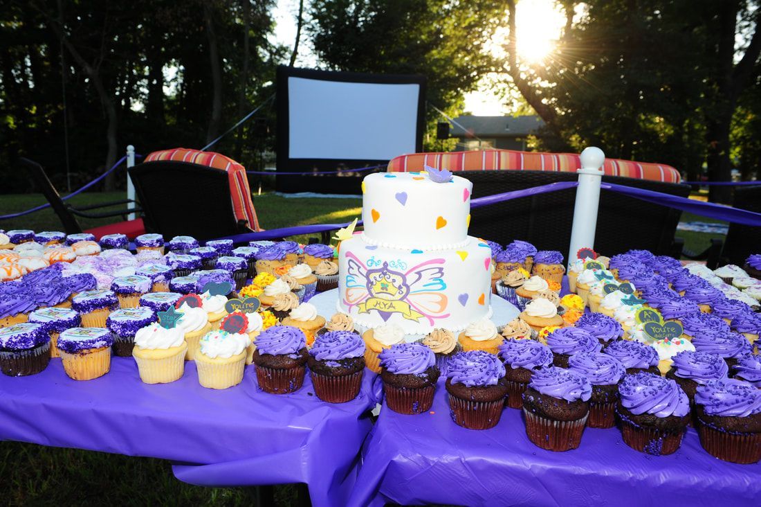 Purple-themed party setup with cake, cupcakes, and outdoor movie screen.