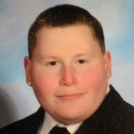 Man with short dark hair, wearing a suit and tie, smiling.