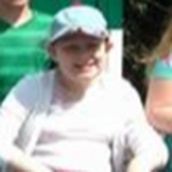 Person wearing a light blue hat and white sweater smiling outdoors.