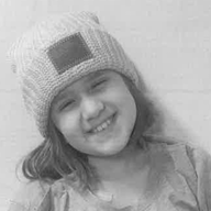 Girl with long hair smiling and wearing a beanie.