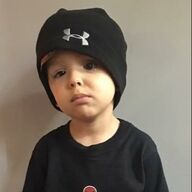 Young child wearing a black beanie and shirt, looking at the camera with a neutral expression.