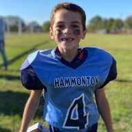 Boy in Hammonton football jersey with missing tooth on a field.