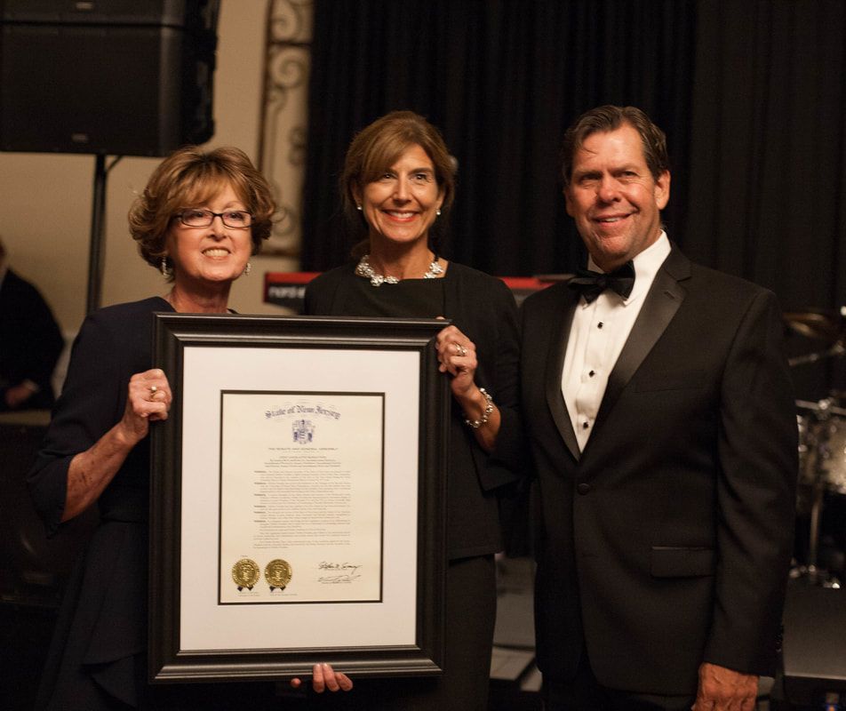 Three people holding framed certificate at formal event.