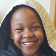 Smiling person in hood, looking directly at the viewer.