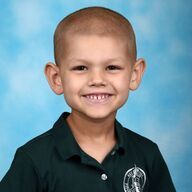 Smiling child wearing a green polo shirt, against a blue background.