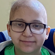 Person with glasses, shaved head, smiling, wearing green shirt, indoors.