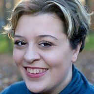 Smiling person with short, light-streaked hair, outdoors.